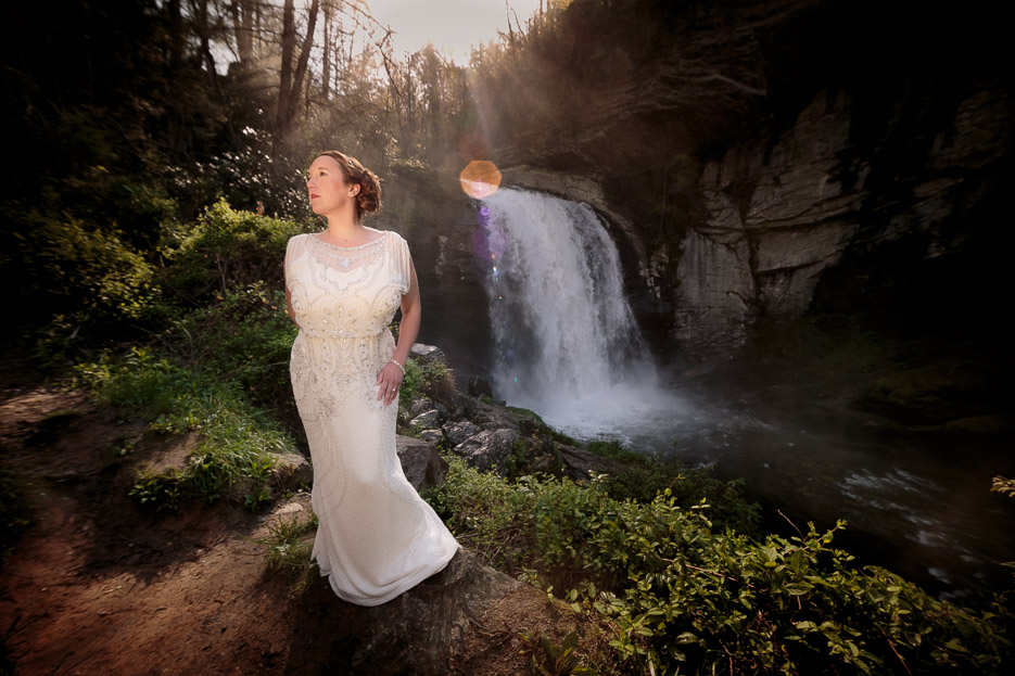 Bride in wedding dressing standing near Pisgah National Forest waterfall during bridal session
